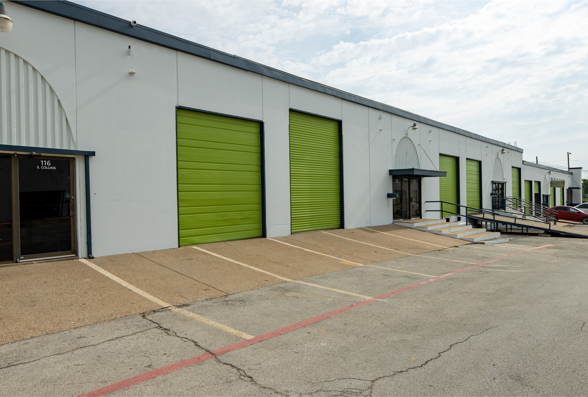 A row of office spaces with a paved parking lot in front of it.