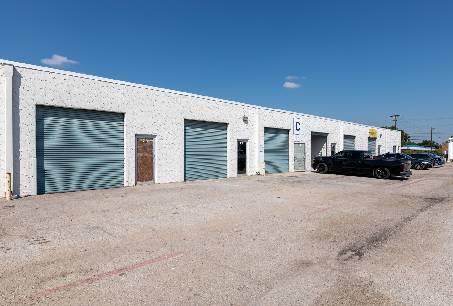 A row of office spaces with a paved parking lot in front of it.