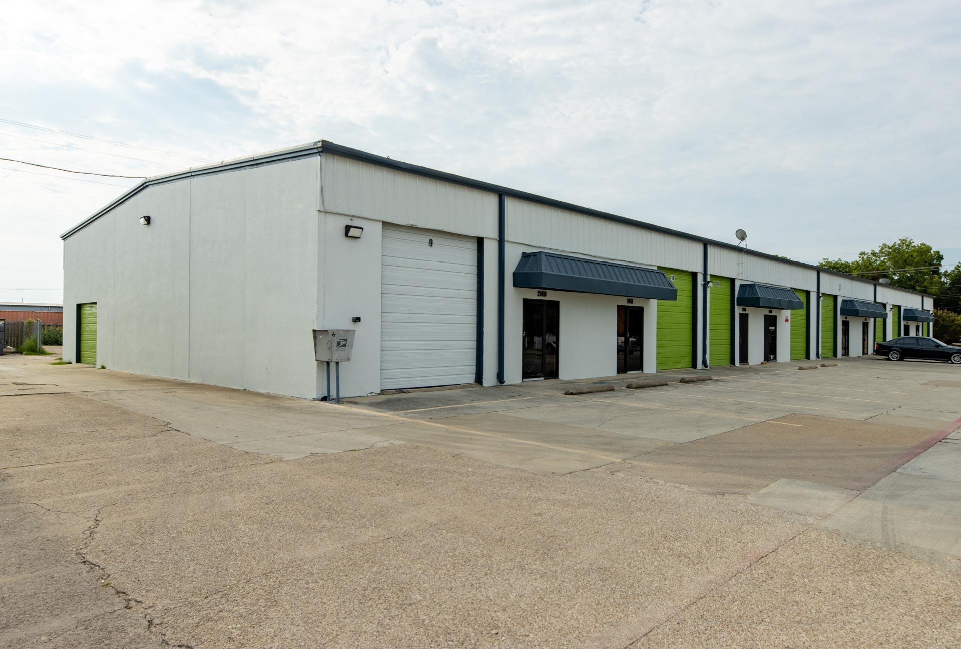 A row of office spaces with a paved parking lot in front of it.