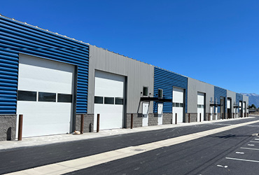 A row of office spaces with a paved parking lot in front of it.