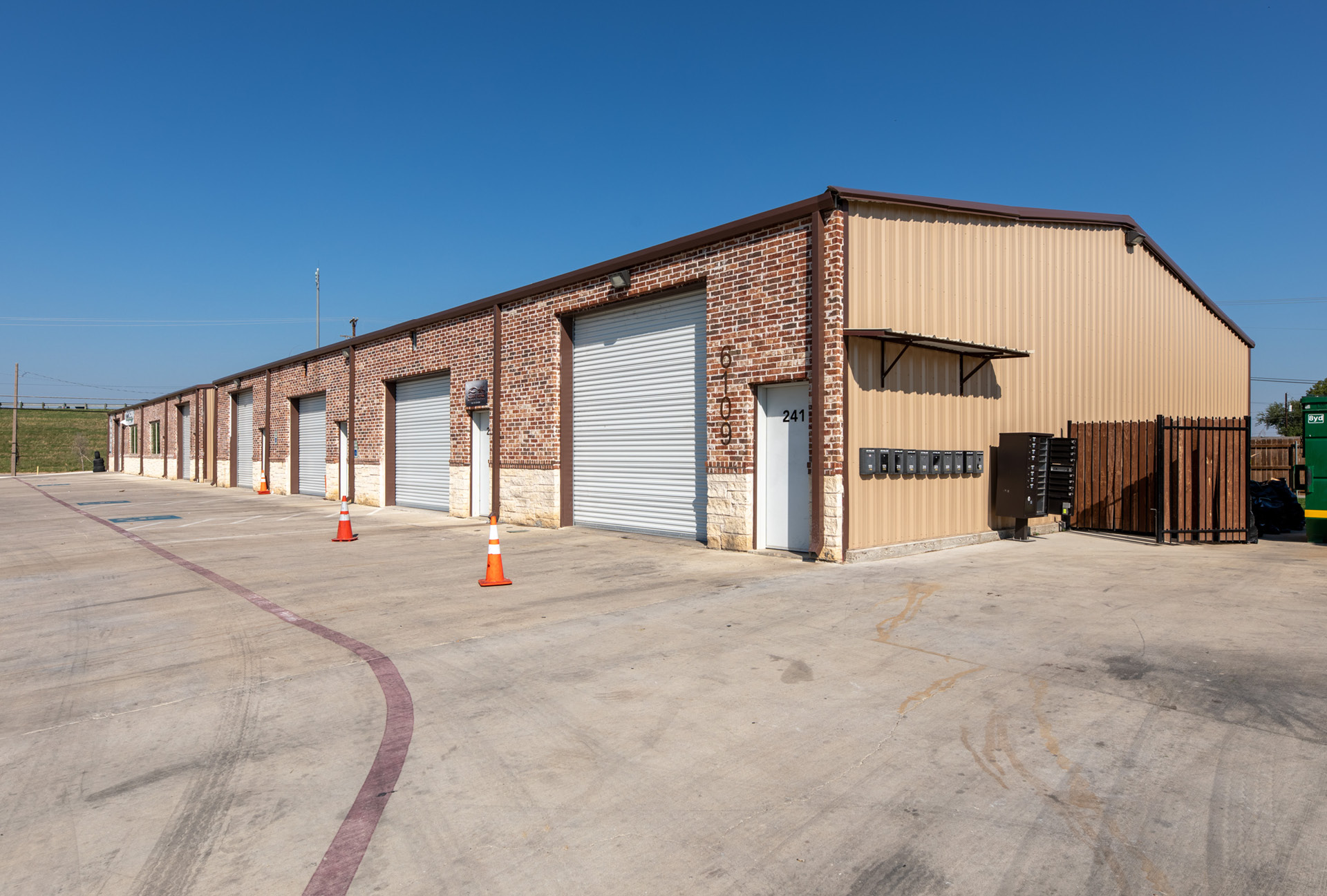 A row of office spaces with a paved parking lot in front of it.