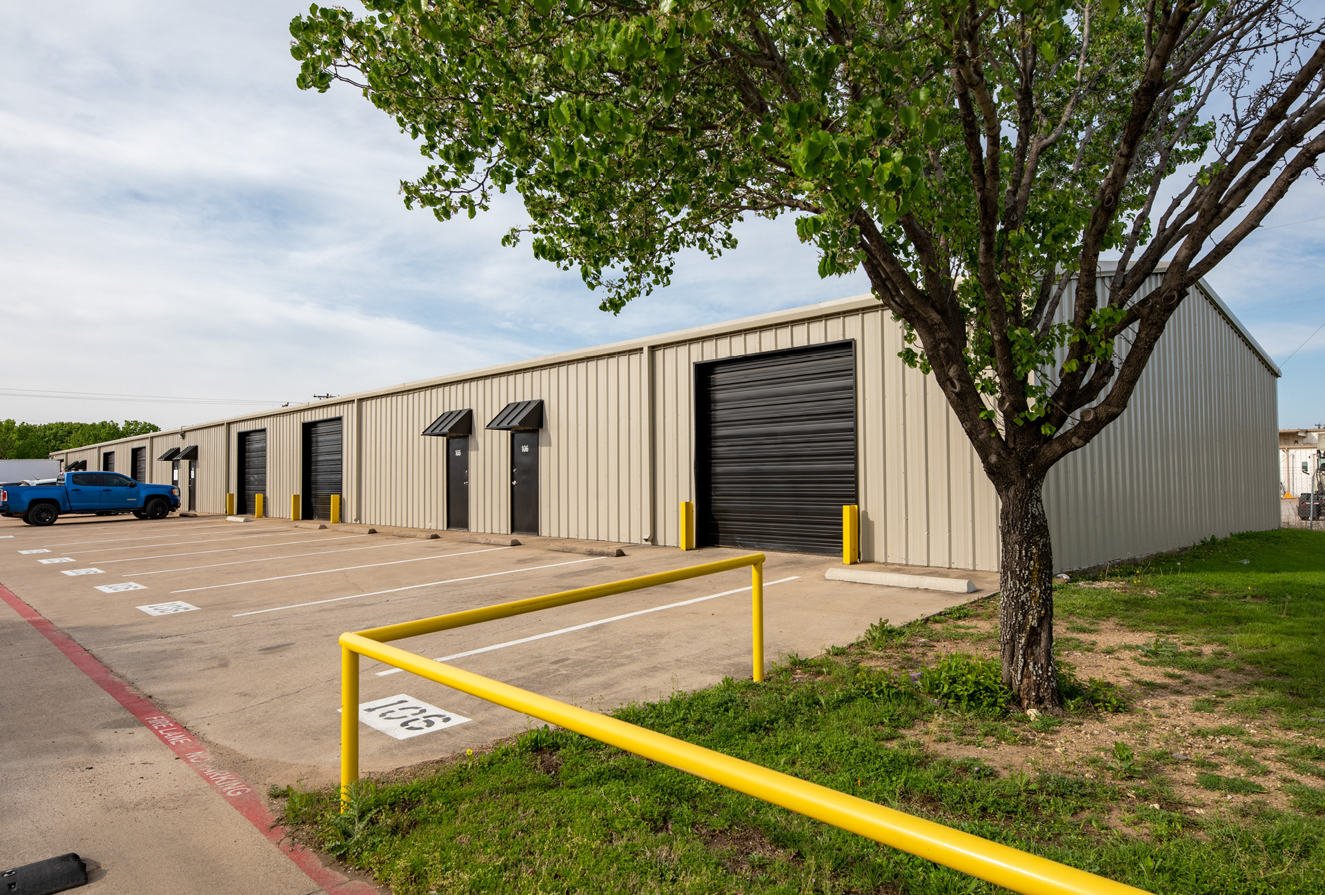 A row of office spaces with a paved parking lot in front of it.