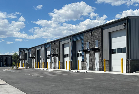A row of office spaces with a paved parking lot in front of it.